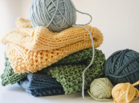 image of a stack of knitted yard in shades of yellow, green, and blue