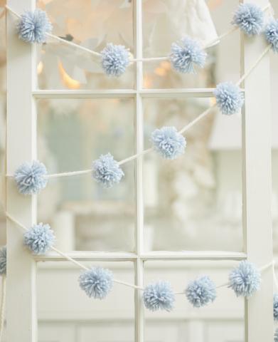 pale blue pom pom garland hanging in window