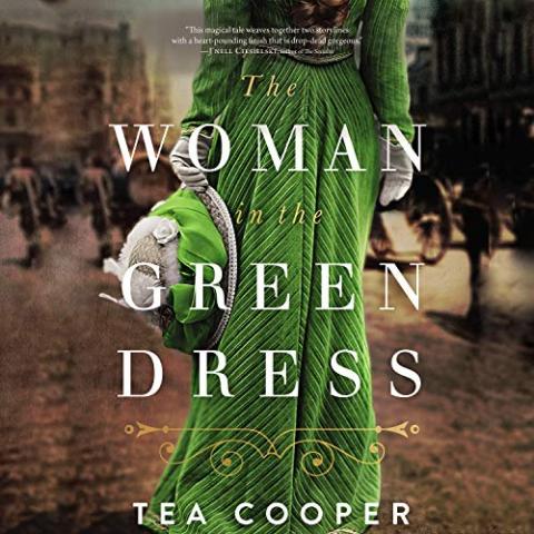 Backside of woman in long green dress holding a hat w/ green ribbon trim